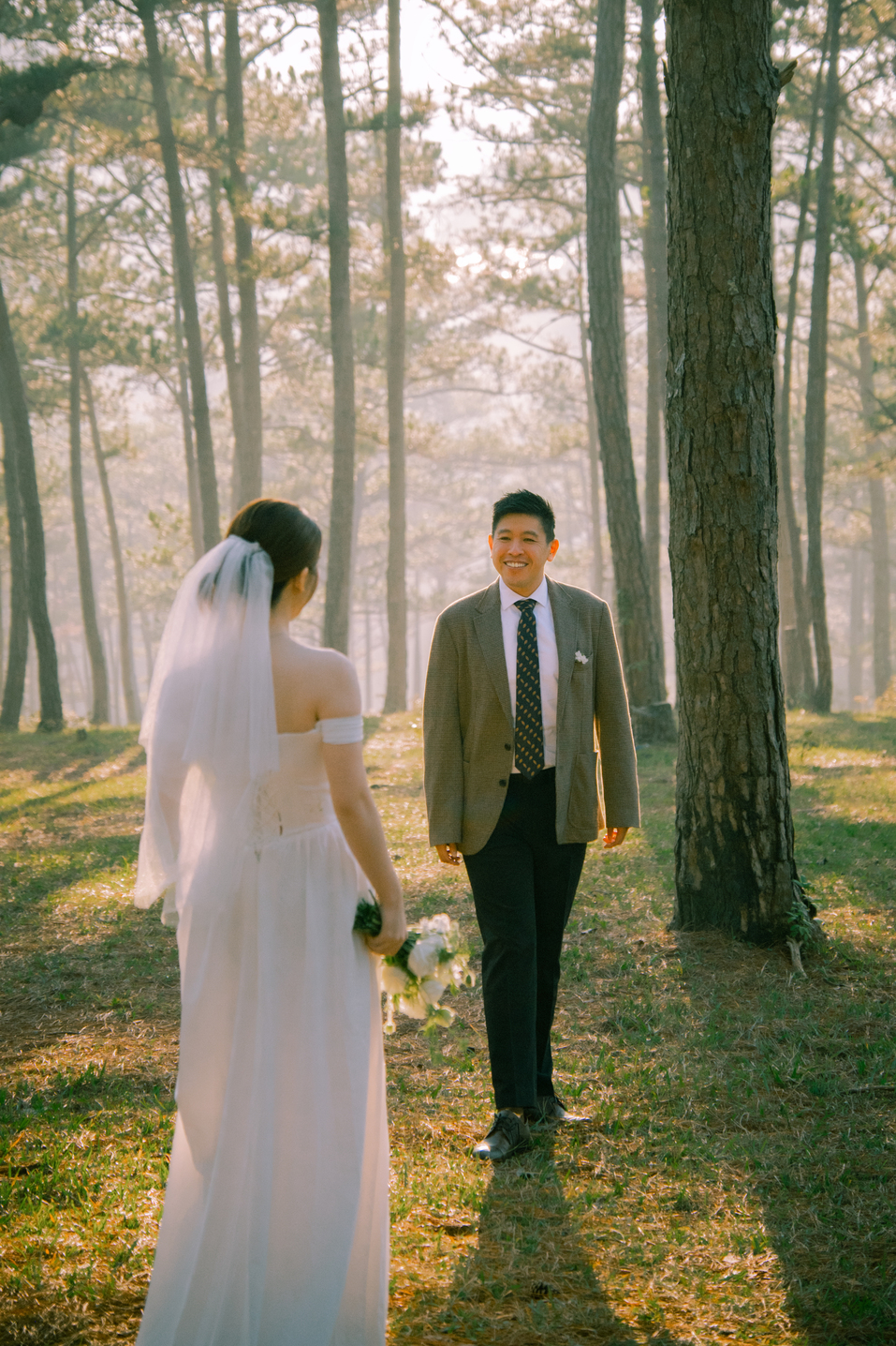 The couple walking hand in hand deeper into the pine forest at golden hour